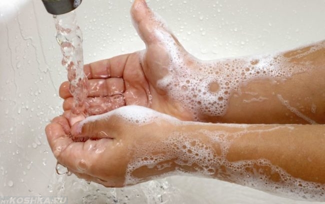 Мытье рук под краном над белой раковиной