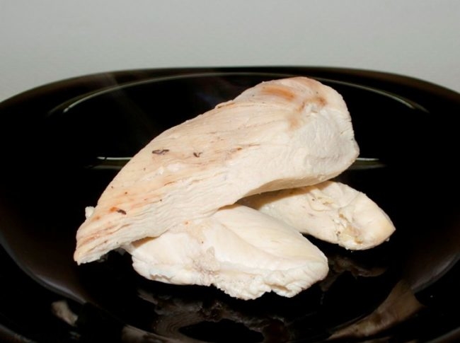 Белое куриное мясо на черной тарелке