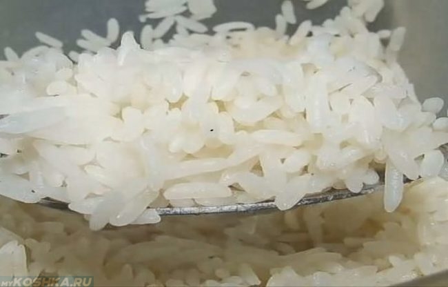 Разваренный рис в ложке над тарелкой